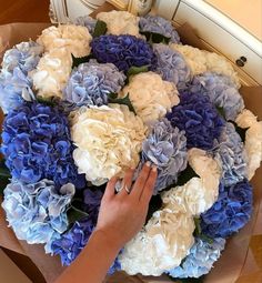 a bouquet of blue and white flowers is being held by a woman's hand