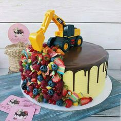 a birthday cake with a construction truck on top and fruit toppings all around it