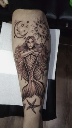 a woman's leg with a tattoo on it and an image of a mermaid holding a starfish