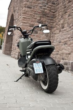 a motorcycle is parked on the sidewalk near a brick wall