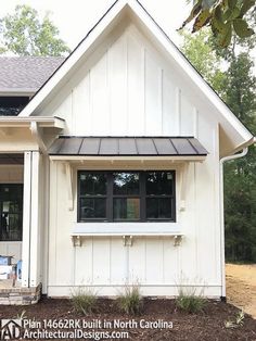 a white house with black trim and windows on the front door is surrounded by mulch