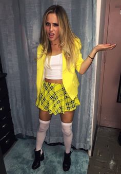 a woman in yellow jacket and plaid skirt posing for the camera with her hands out