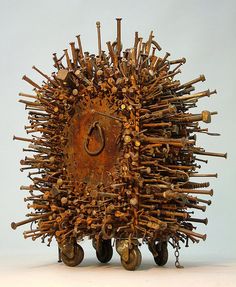 a sculpture made out of wooden sticks and other objects on wheels with handles, chains and hooks attached to them