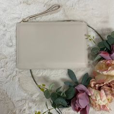 a white purse sitting on top of a table next to flowers