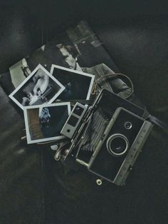 an old camera and some polaroid pictures on a black couch with a leather bag