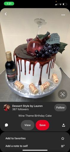 a cake with chocolate icing and fruit on top, sitting next to a bottle of wine