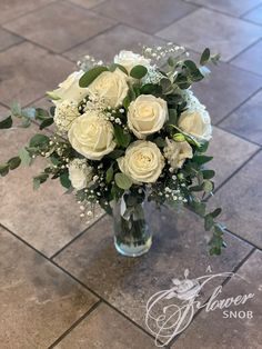 a vase filled with white flowers on top of a tiled floor next to a tile floor