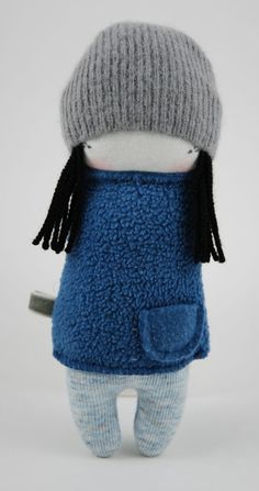 a stuffed doll wearing a blue sweater and hat