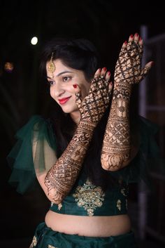 a woman with henna on her hands and arms is smiling at the camera while wearing a green outfit