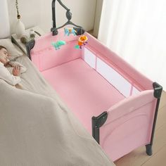 two children's beds with pink and grey bedding, one has a baby in it