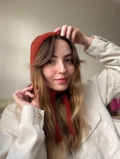 a woman wearing a red hat and scarf is posing for the camera with her hands on her head