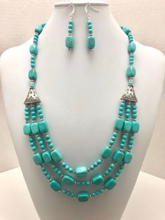 DESCRIPTION:  This statement necklace features three strands of turquoise magnesite nugget beads spaced with coordinating round beads. The three-stranded center portion ends into two ornate silver cones. Out from the silver cones is a single strand of turquoise magnesite nugget beads and round beads. Small silver beads accent the silver cones. The necklace ends with a silver s-hook clasp (see the fourth photo).  Stand out with this bold turquoise magnesite necklace! Turquoise looks great with so Luxury Single Strand Turquoise Beaded Necklace, Photo Stand, Unique Statement Necklace, Turquoise Statement Necklace, Handmade Jewlery, S Hook, Necklace Turquoise, Bracelet Diy, Free Earrings