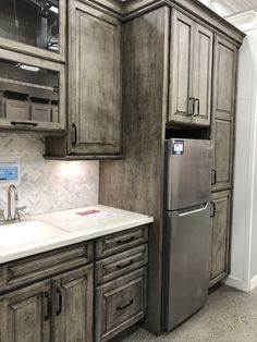 a kitchen with gray cabinets and a silver refrigerator freezer next to a white counter top