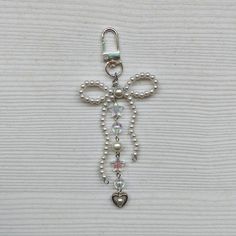 a cross made out of pearls and beads on a white surface with a heart hanging from it