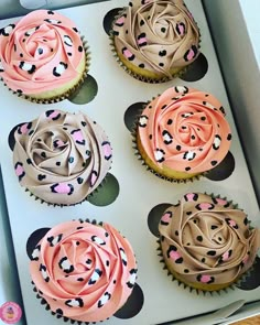 four cupcakes with pink and brown frosting in a box