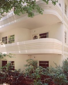 an apartment building with balconies on the second floor and trees in front of it