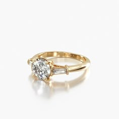 a yellow gold ring with an oval diamond and baguettes