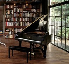 there is a grand piano in the living room with bookshelves and a bench