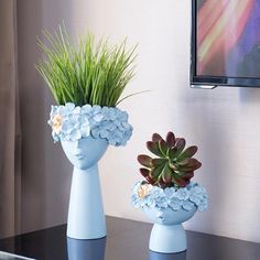 two blue vases with plants in them on a table