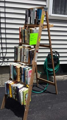 a ladder bookshelf filled with lots of books on the side of a house