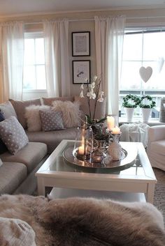 a living room filled with lots of furniture next to a window covered in white curtains