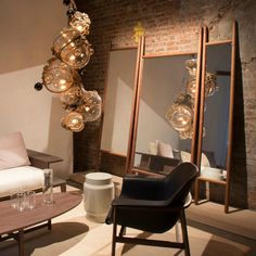 a living room filled with furniture next to a brick wall and mirror on the wall