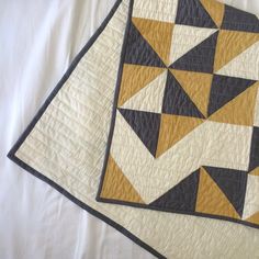 two quilts on top of each other with black, yellow and white squares in them