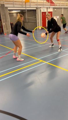 two women playing with hoop balls in an indoor gym