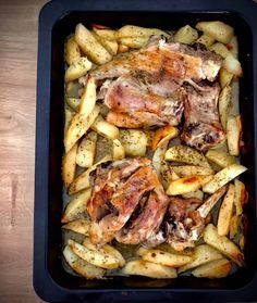 some meat and potatoes in a pan on a wooden table with a knife next to it