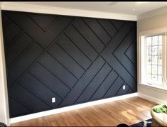 an empty room with wood flooring and black painted wallpaper on the walls, in front of a window