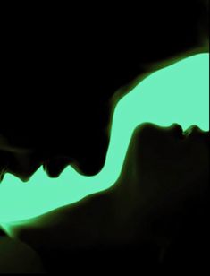 a woman's face is glowing in the dark with green light coming from her mouth