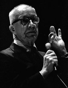 an older man with glasses making the middle finger sign while standing in front of a microphone