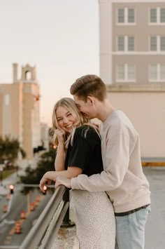 a man and woman standing next to each other on top of a roof looking at each other