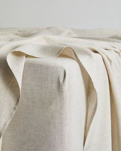 an unmade bed with white sheets and pillows