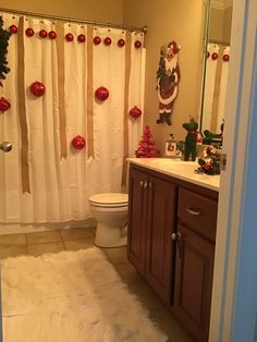 a bathroom decorated for christmas with decorations on the shower curtain, toilet and sink area