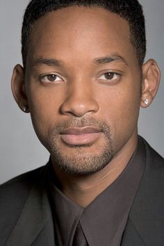 a close up of a person wearing a suit and tie with an earring on