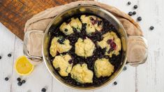 a pot filled with blueberries and dumplings on top of a wooden table