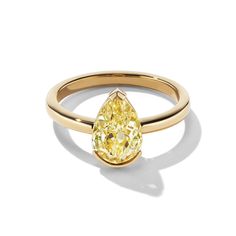 a yellow pear shaped diamond ring with a thin band on the top and bottom, set in