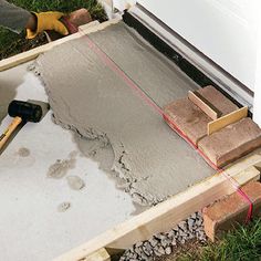 a man is pouring cement into a hole in the ground to build a house with bricks