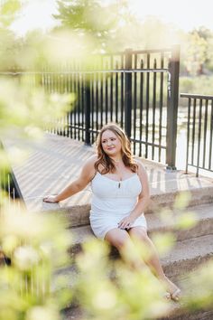 a woman sitting on the steps in front of some bushes