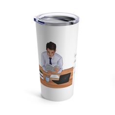 a man sitting at a desk reading a book while wearing a tie and holding a coffee mug