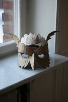 a paper mask sitting on top of a window sill next to a white wall