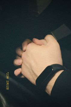 a person with their hand on the wrist of another person wearing a black leather bracelet