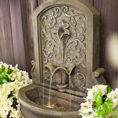 a water fountain surrounded by flowers and greenery