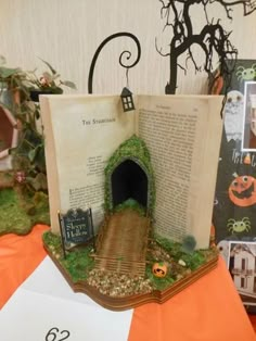 an open book sitting on top of a table covered in fake grass and pumpkins