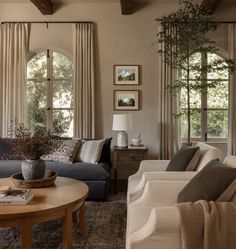 a living room with two couches and a coffee table in front of three windows