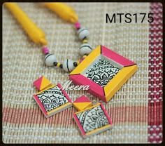 the necklace is next to two yellow and pink beads on a tablecloth with a box