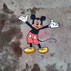 a mickey mouse drawn on the ground with his arms out and hands in the air