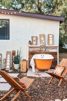 an orange bath tub sitting in the middle of a yard next to lawn chairs and a potted plant