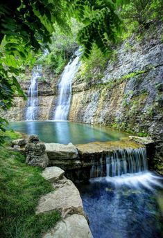 a small waterfall in the middle of a lush green forest